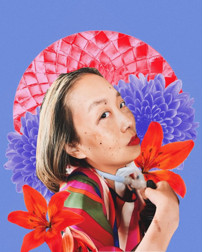 Digital portrait by Jen White-Johnson featuring a photo of Asian American woman with honey blonde hair. She is in a wheelchair and there is a tracheostomy at her neck connected to a ventilator. She is wearing a silky multicolored shirt and a bold red lip color. She is looking intently at the camera with the heat of a thousand suns. Behind her are red and purple flowers with a red circle in the background framing her face like a warm sun. The background of the portrait is purple.